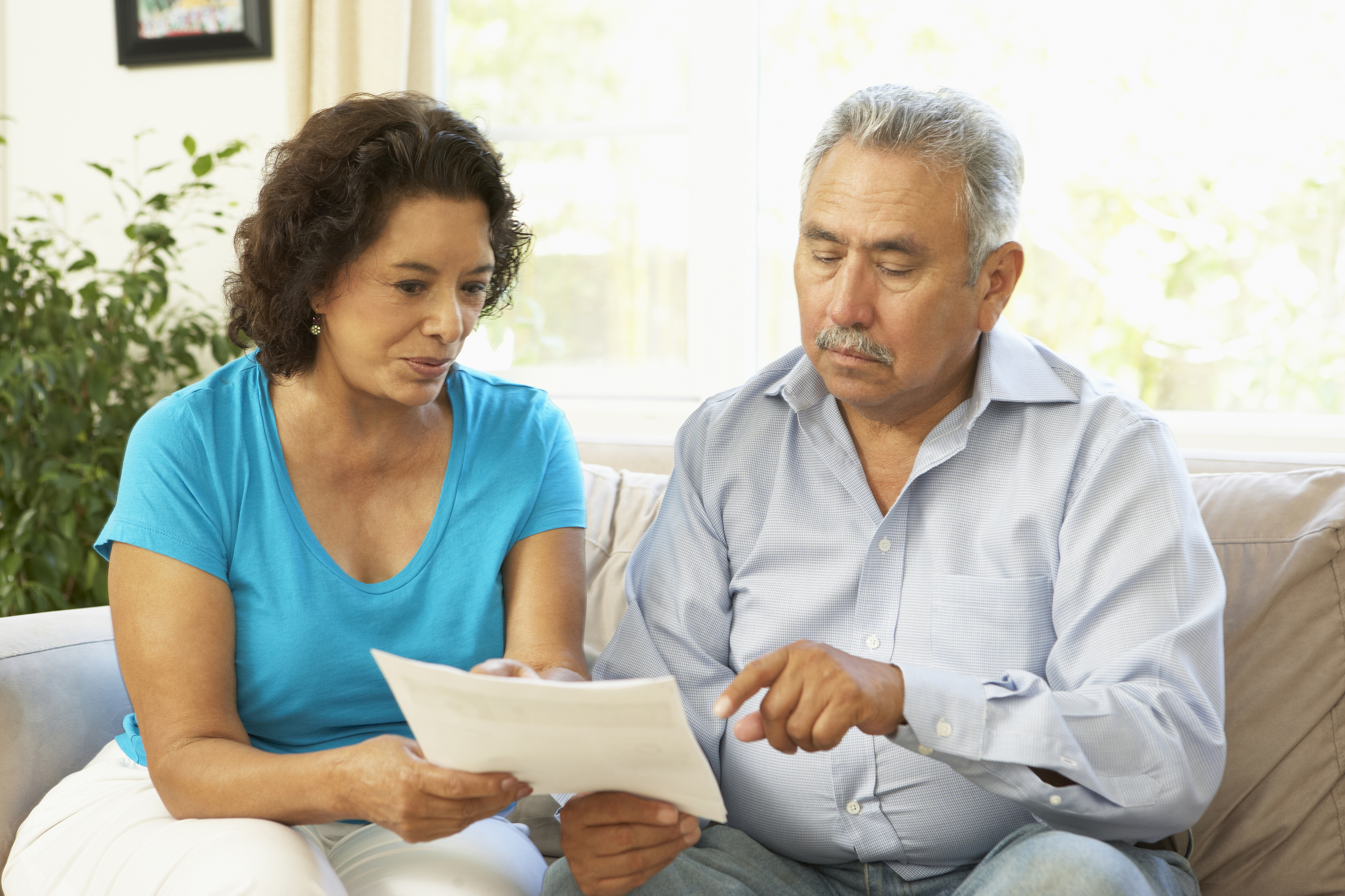 photo of older man assited by a woman looking over paperwork